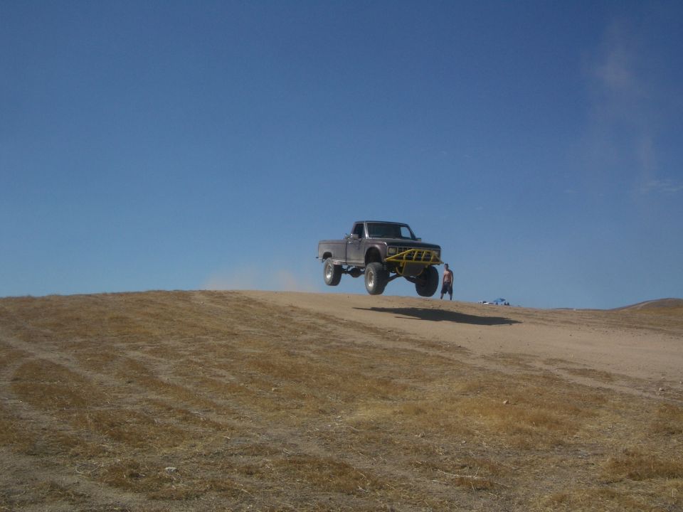 Brown 1985 Ford Ranger jumping mid-air with yellow bumper guard