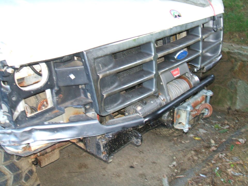 Front grille and bumper of a Ford truck with a winch installed. Grille has horizontal bars and a blue Ford oval emblem