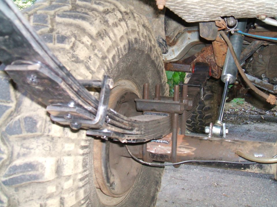 Close-up of a modified rear leaf spring suspension with a new U-bolt setup and shock absorber