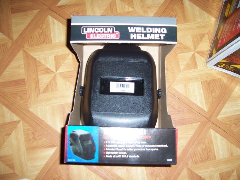 1983 Ford Bronco - A Lincoln Electric welding helmet is shown in its original packaging on a wood-grain floor.