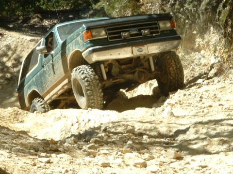 1990 Ford Bronco - 1990 Ford Bronco navigating a challenging off-road trail.