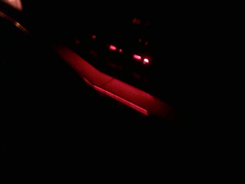 1985 Ford Crown Victoria LTD - The interior of a vehicle is dimly lit, with a prominent red glow emanating from the dashboard area.