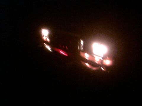 1985 Ford Crown Victoria LTD - A dark photo captures illuminated vehicle lights, with headlights and taillights visible.