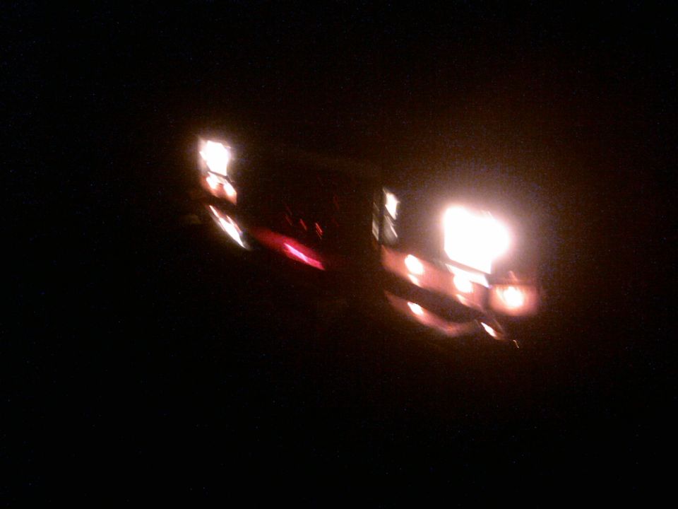 Vehicle lights at night, showing bright headlights and red taillights