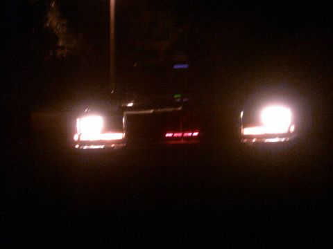 1985 Ford Crown Victoria LTD - Rear view of a 1985 Ford Crown Victoria LTD at night, showing illuminated taillights.
