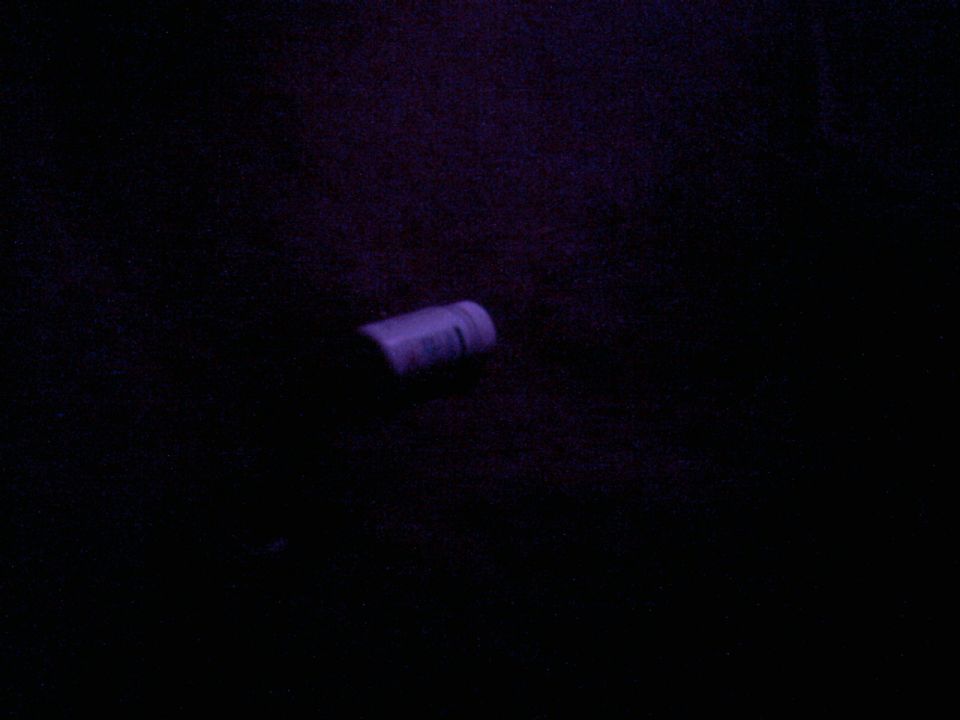 Purple cylindrical object with a metallic band, lying on a dark surface