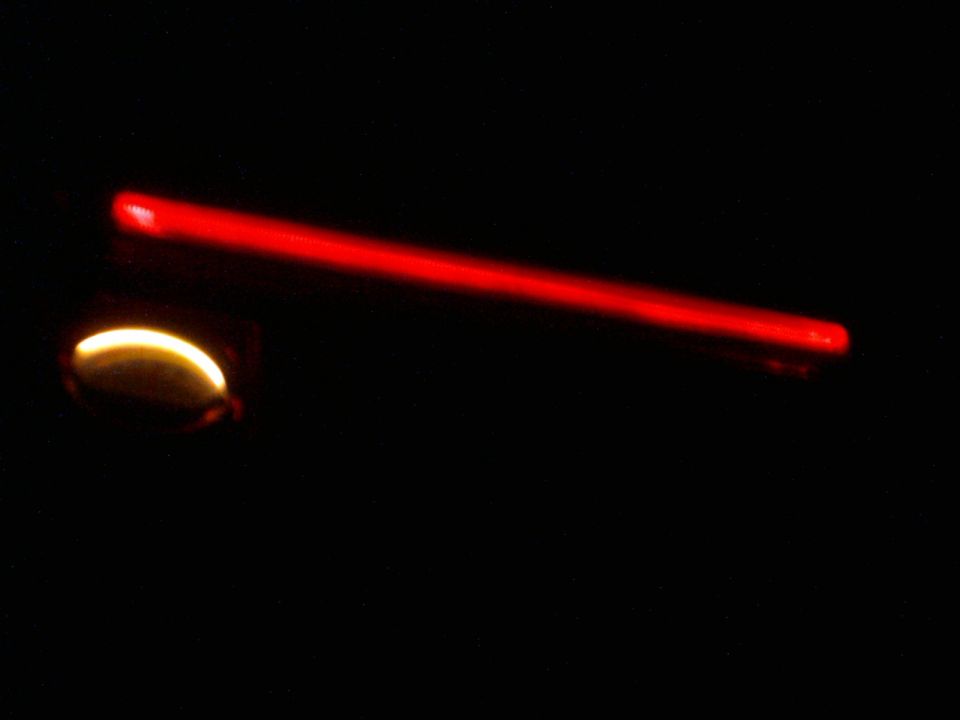 Red gauge needle illuminated against black background