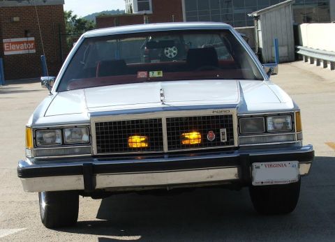 1985 Ford Crown Victoria LTD - This 1980s Ford sedan is shown from the front, a prominent grille and amber turn signals.