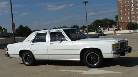 1985 Ford Crown Victoria LTD - Side view of a white sedan with chrome trim and black wheels.