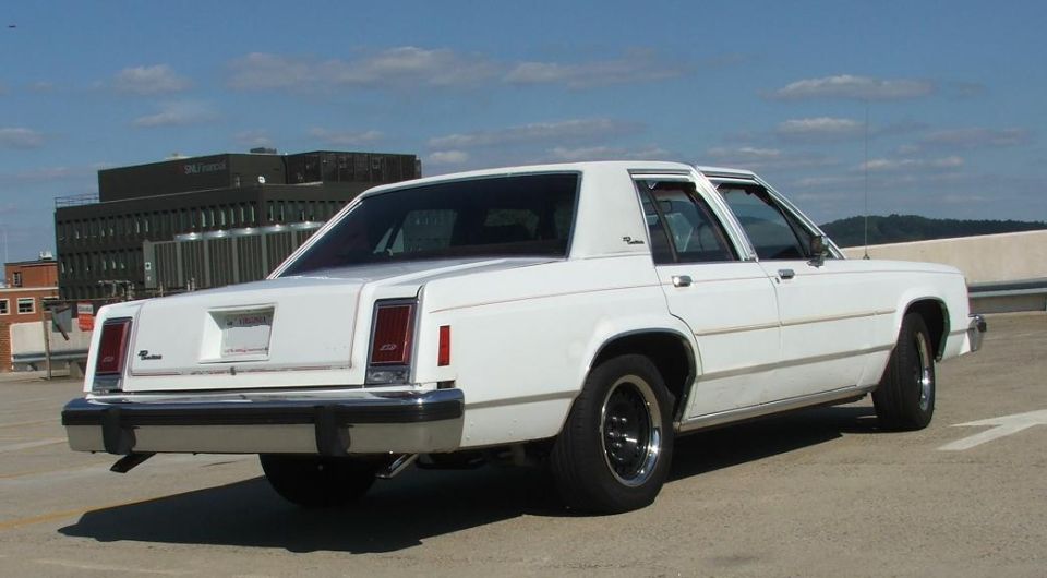White sedan parked on a rooftop with a building in the background