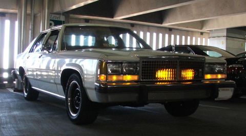 1985 Ford LTD Crown Victoria - Front view of a white 1980s Ford sedan parked in a multi-level garage.