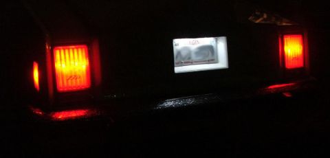 1985 Ford LTD Crown Victoria - The rear of a vehicle is shown at night, with its license plate and taillights illuminated.