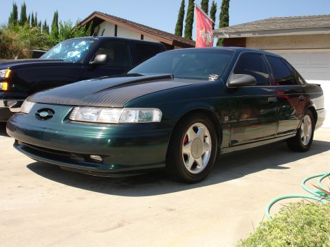 1993 Ford Taurus - Green sedan with carbon fiber hood and aftermarket wheels parked in a driveway.