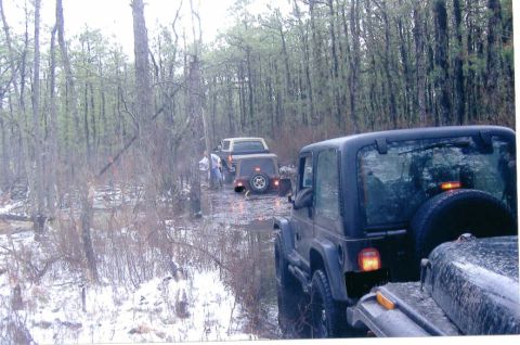 1997 Jeep TJ - Multiple Jeep Wranglers navigate a wet and snowy forest trail.