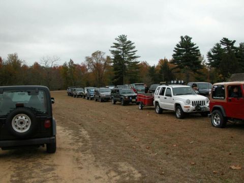 1997 Jeep TJ - A convoy of Jeeps is parked on a dirt road, with autumn foliage visible in the trees.