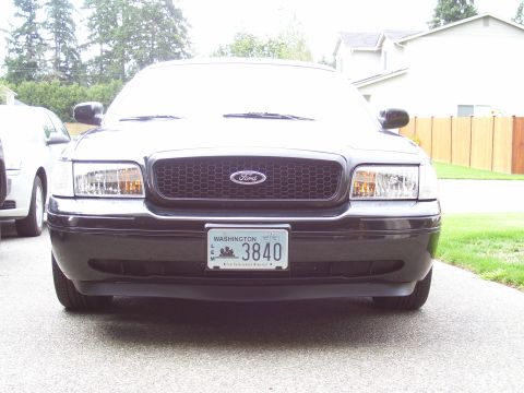 2002 Ford Crown Victoria - A black Ford Crown Victoria is parked in a driveway, with another vehicle partially visible to the left.