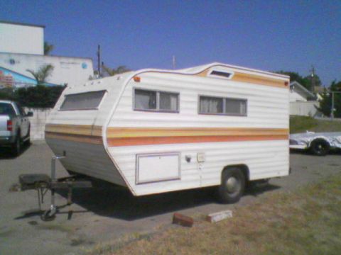 1984 Ford Bronco - A vintage travel trailer is parked outdoors under a clear blue sky.