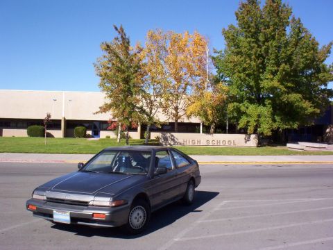 1986 Honda Accord - A 1986 Honda Accord coupe is parked in front of a high school building on a sunny day.