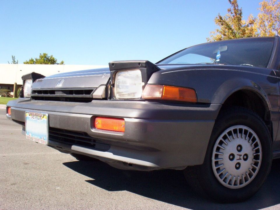 Low front view of gray Honda Accord with pop-up headlights up and Nevada plate