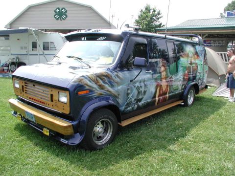 1978 Ford Mustang II - Van with custom mural art on its side, parked outdoors.