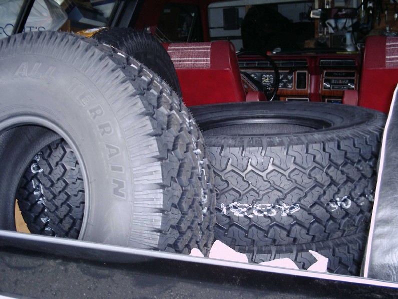 Spare tires stacked inside a vehicle with red seats and wood-grain dashboard