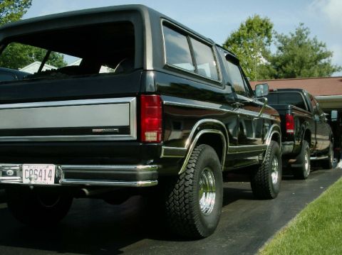 1984 Ford Bronco - Rear view of a black SUV parked next to a black pickup truck.