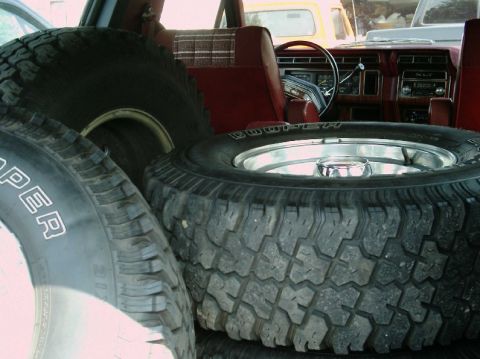 1984 Ford Bronco - Spare tires fill the interior of this 1984 Ford Bronco, with a glimpse of a yellow truck in the background.