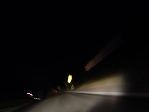 1986 Honda Accord - The road ahead is dimly lit by headlights and streetlights, with blurry lights in the distance.