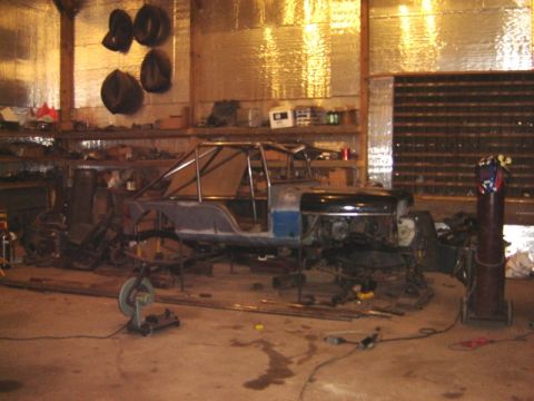 1992 Ford Bronco - A vehicle chassis with a roll cage is seen in a workshop, appearing to be in the process of construction or modification.