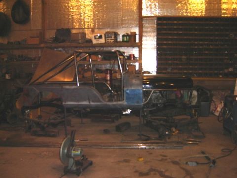 1992 Ford Bronco - Jeep CJ-6 body undergoing modification with a custom roll cage in a workshop setting.