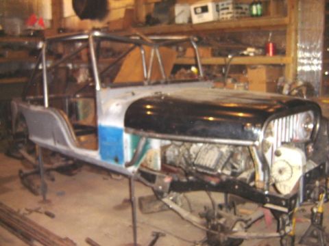 1992 Ford Bronco - This Jeep CJ-5 body is in a workshop, supported by stands and showing its frame and engine components.