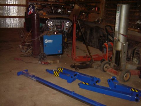 1992 Ford Bronco - A black Jeep CJ-7 is parked in a workshop with various tools and equipment, including a Miller welding machine and car lifts.