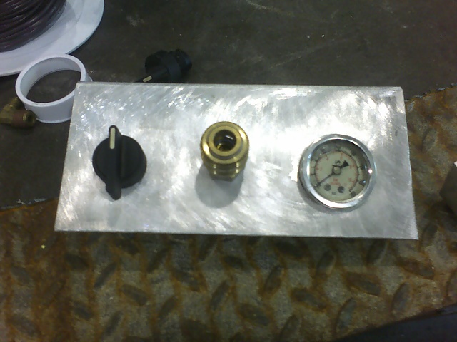 Aluminum panel with black knob, brass air fitting, and pressure gauge on a shop workbench