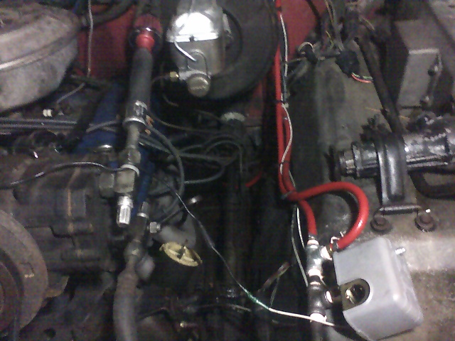 Engine bay with blue engine, chrome brake booster, red-capped distributor, and wiring in a 1978 Ford Bronco