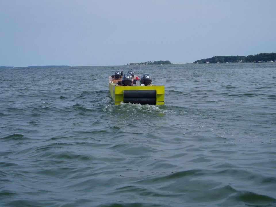 Yellow boat with four outboard motors moving away on the water