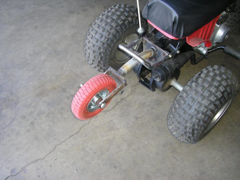 1900 Honda Big Red - This ATV has a black seat and red bodywork, with a prominent engine and exhaust system visible.