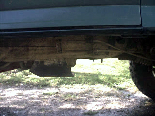 Underside of dark green SUV showing frame and suspension components