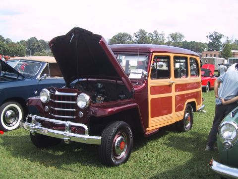 1968 Shelby GT500 - A maroon and wood-paneled station wagon is displayed with its hood open at an outdoor car show.