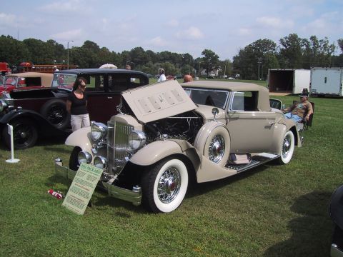 1968 Shelby GT500 - A tan 1935 Packard convertible is displayed with its hood open at a car show.