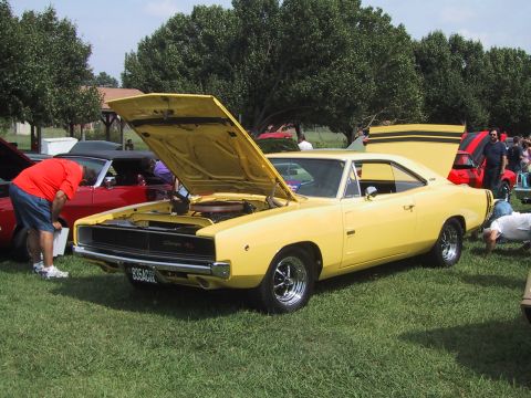 1968 Shelby GT500 - A yellow 1968 Dodge Charger is displayed with its hood open at a car show, alongside other vehicles.