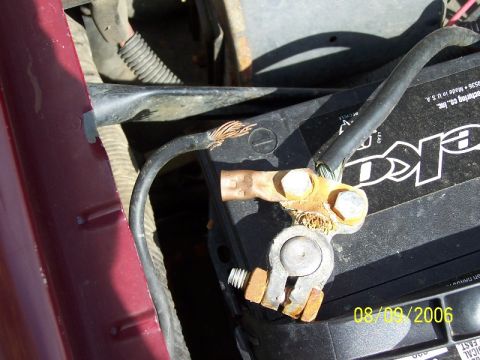 1992 Ford Bronco - A close-up view of a car battery terminal shows corroded connections and damaged wiring.