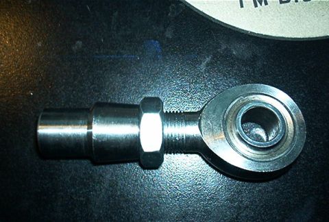 1986 Ford Bronco - A close-up view of a metal rod end bearing with a threaded shaft, resting on a dark surface.