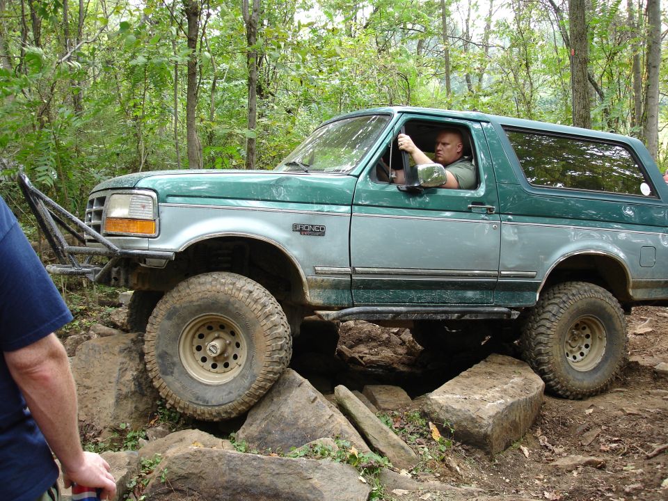 1996 Ford Bronco side view, green and silver, off-roading over rocks