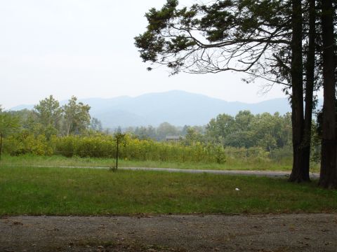 1996 Ford Bronco - A hazy mountain range forms the backdrop to a rural landscape trees and a field.