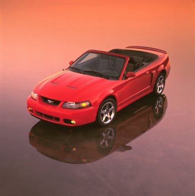 2003 Ford Mustang - A red 2003 Ford Mustang convertible is shown from a three-quarter front angle against a gradient orange background.