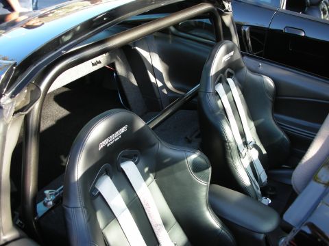1992 Ford Crown Victoria - Interior view of a car with racing seats and a roll cage, with another black vehicle visible outside.