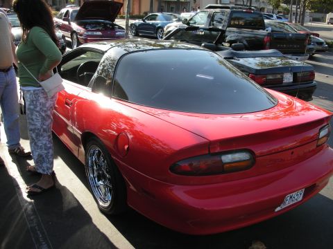 1992 Ford Crown Victoria - A red coupe with a black t-top roof is parked in a lot, with other vehicles visible in the background.