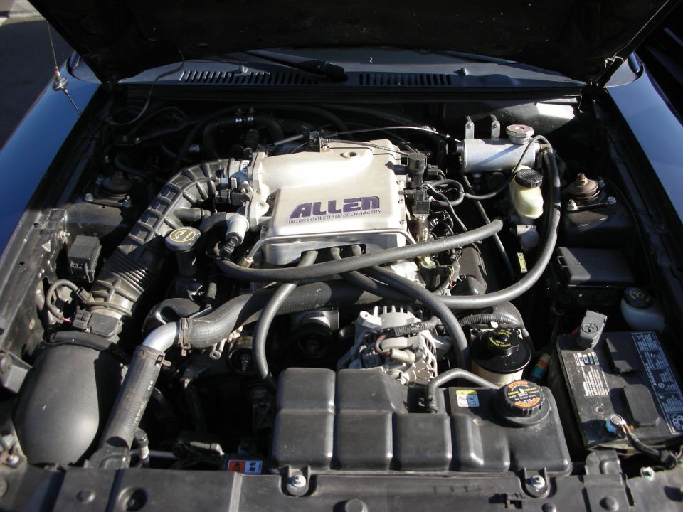 Engine bay with a silver "ALLEN" supercharger and black hoses