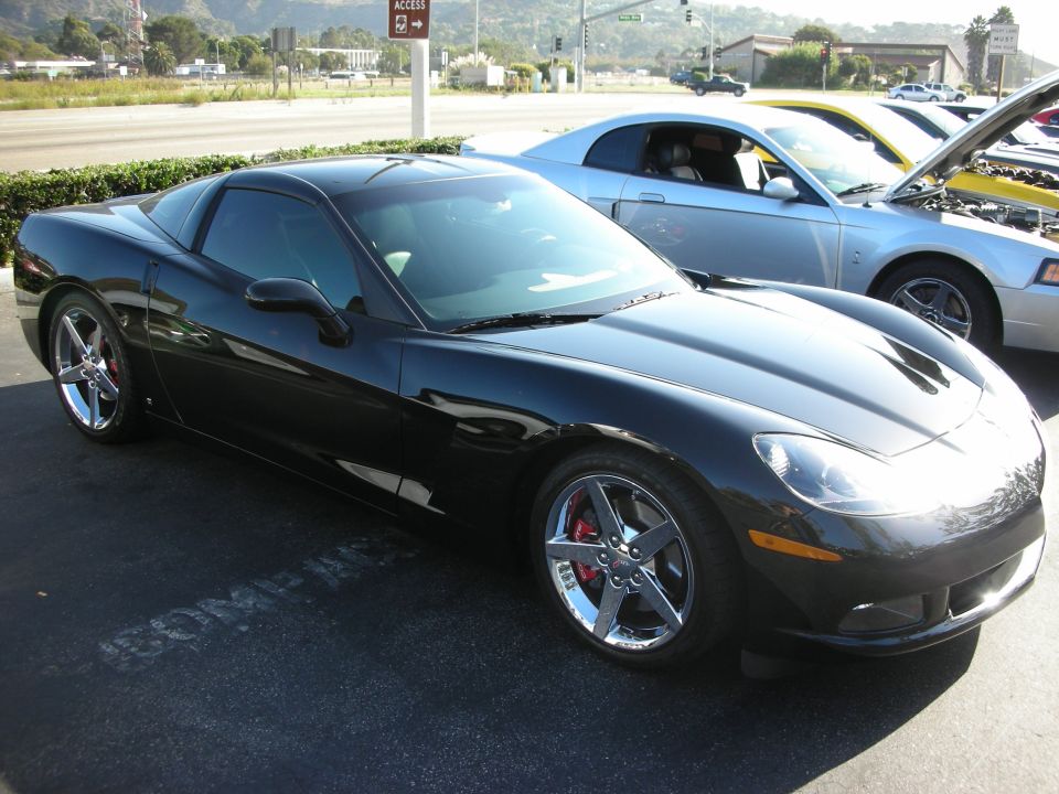 Black Chevrolet Corvette C6 parked next to a silver Ford Mustang