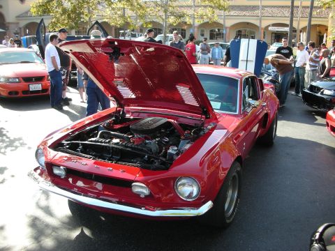 1992 Ford Crown Victoria - Classic red Ford Mustang at a car show, hood raised to display the engine.